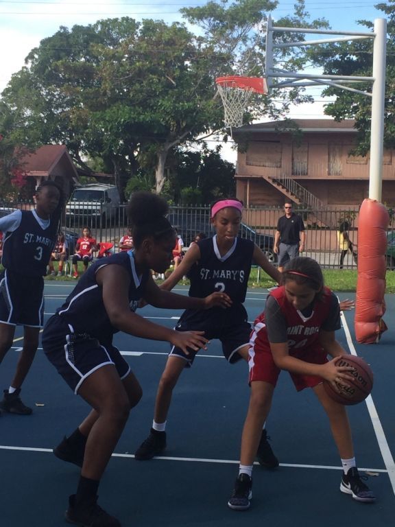 A group of girls are playing basketball and one has the number 2 on her jersey