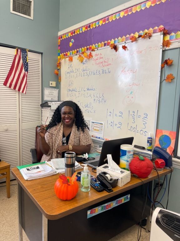 A woman is sitting at a desk in front of a white board