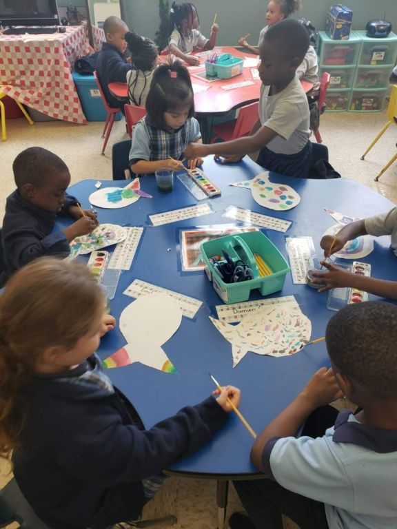 A group of children are sitting around a table painting