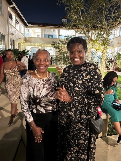 Two women are posing for a picture in front of a building at night.