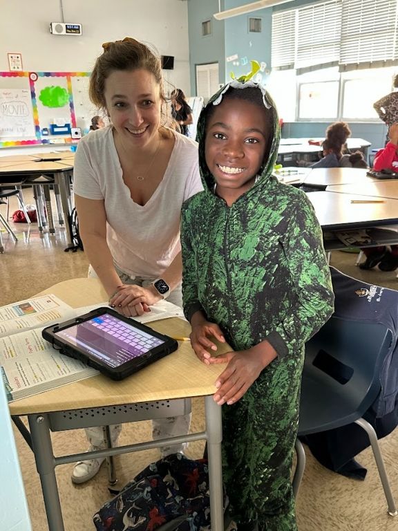 A woman and a boy are standing next to each other in a classroom.