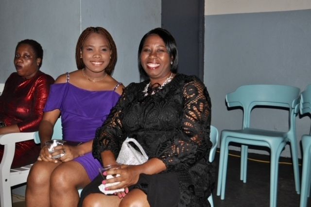 Three women are sitting in chairs and smiling for the camera