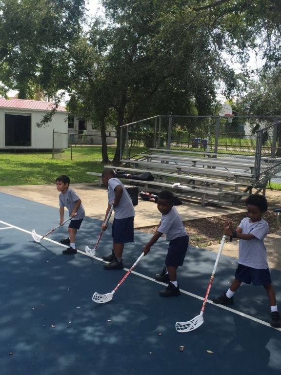 A group of young boys are playing lacrosse on a court