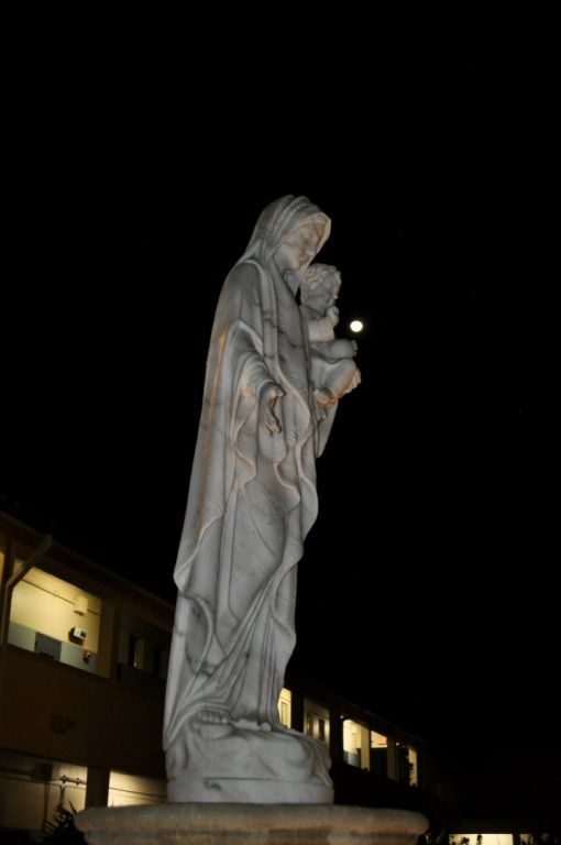 A statue of a woman holding a baby in her arms at night.