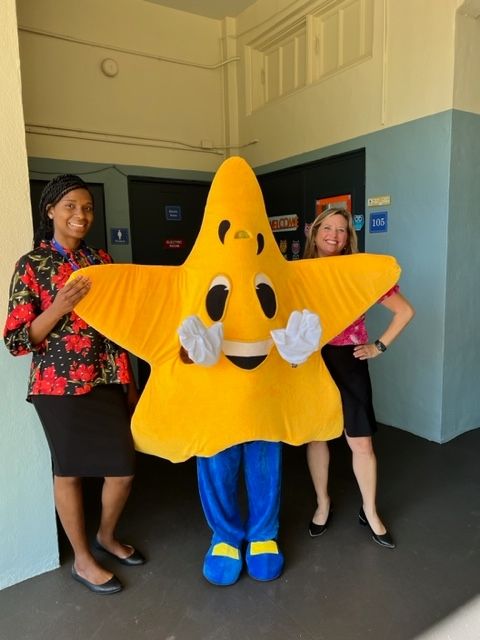 Two women standing next to a yellow star mascot