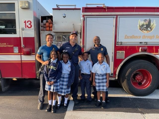 A group of people standing in front of a fire truck with the number 13 on it
