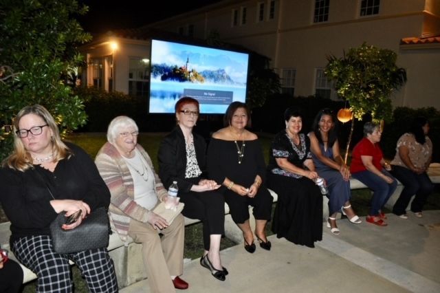 A group of women are sitting in front of a large screen