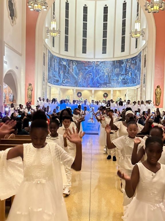 A group of children in white dresses are dancing in a church.