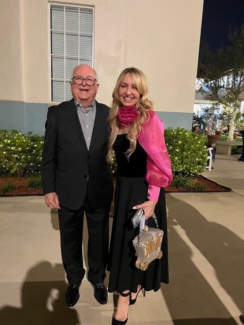 A man and a woman are posing for a picture in front of a building