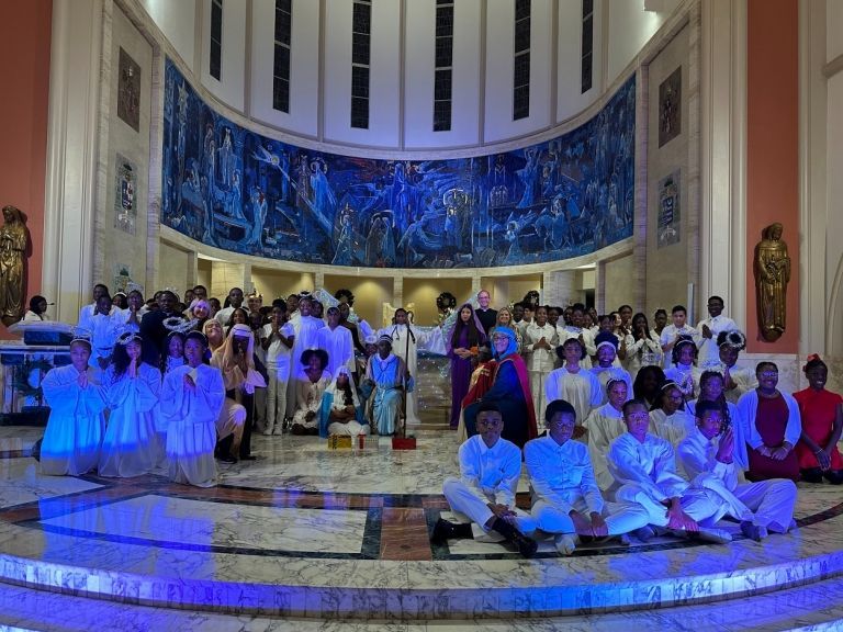 A large group of people are sitting on the floor in a church.
