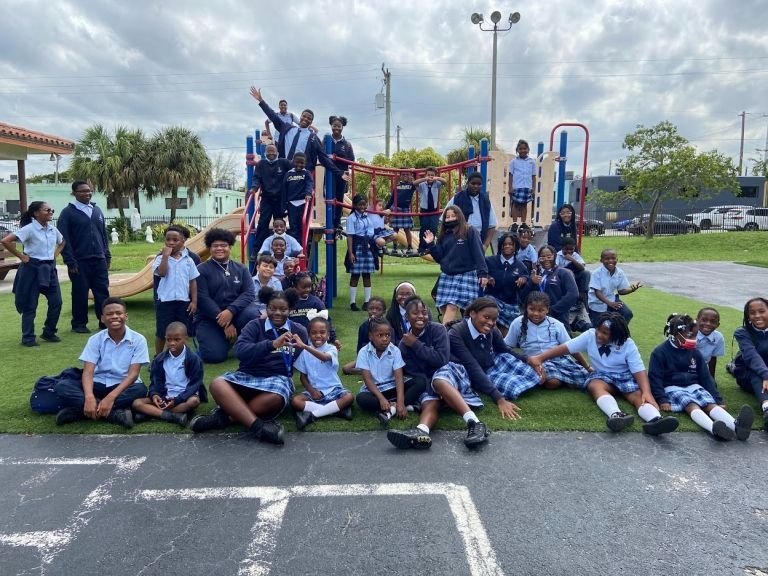 A group of children are posing for a picture in front of a playground.