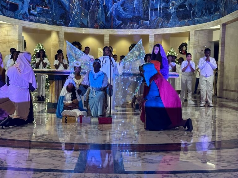 A group of people are standing in a room with a christmas tree in the background