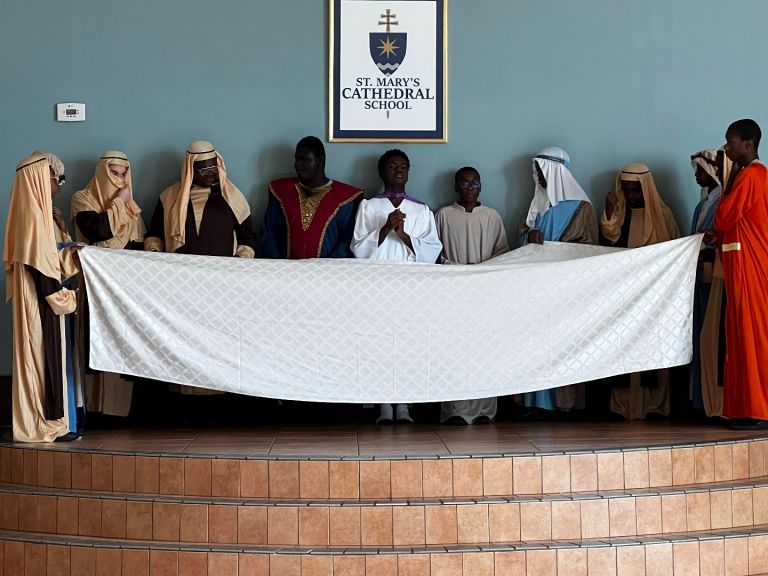 A group of people standing in front of a sign that says always catholic