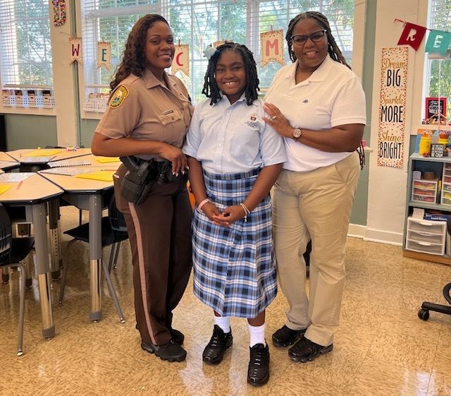 A girl in a plaid skirt is posing for a picture with two women