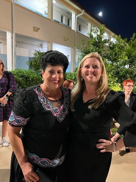 Two women are posing for a picture in front of a building.
