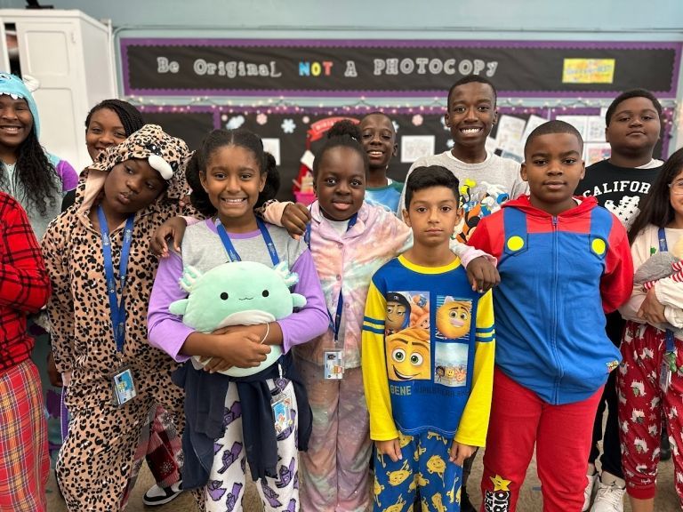 A group of children in pajamas are posing for a picture in a classroom.