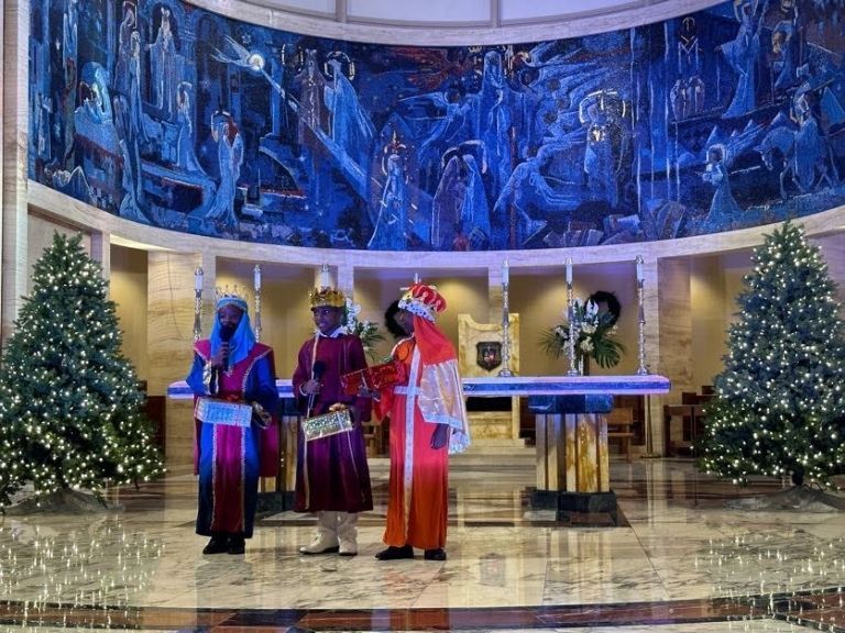 Three kings are standing in front of a christmas tree in a church.