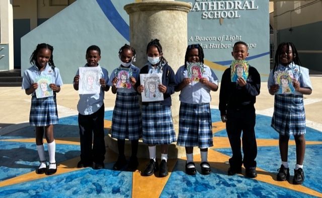 A group of children are standing in front of a cathedral school