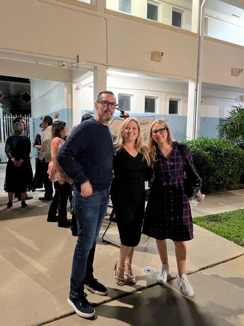 A man and two women are posing for a picture in front of a building.