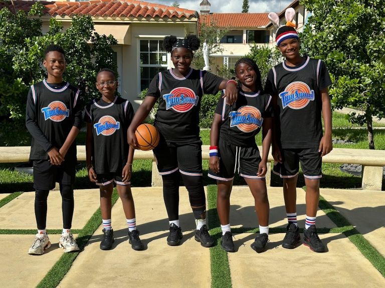 A group of kids wearing space jam jerseys pose for a picture