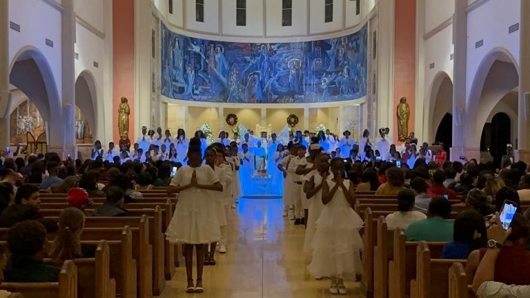 A large group of people are standing in a church.