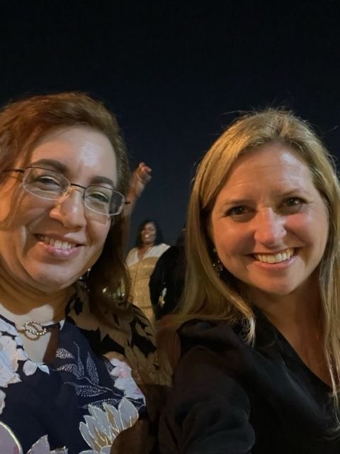 Two women are posing for a picture together and smiling at the camera.