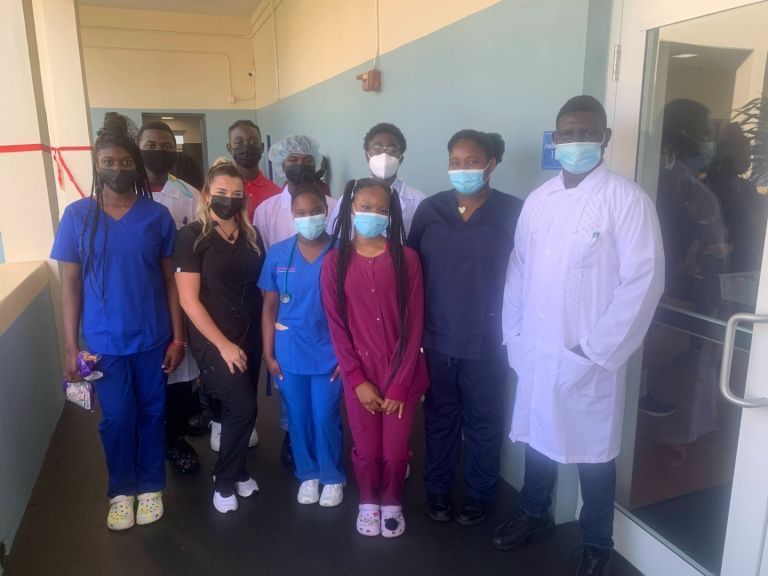 A group of people wearing masks are posing for a picture in a hallway.