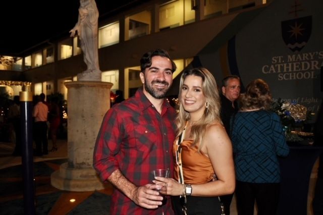 A man and a woman are posing for a picture in front of a building that says st mary 's cathedral school