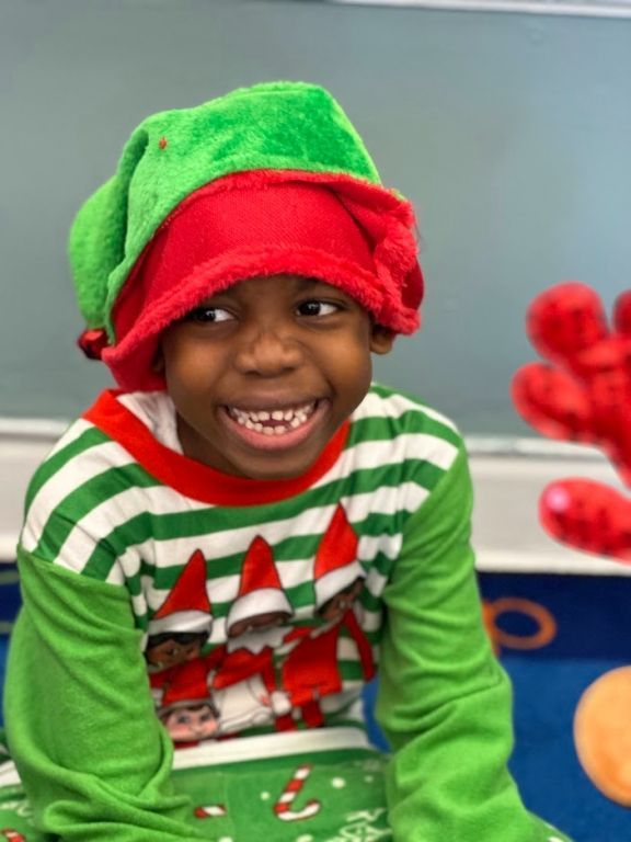 A young boy dressed as an elf on the shelf