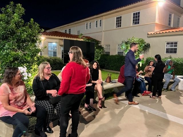 A group of people are gathered outside of a building at night.