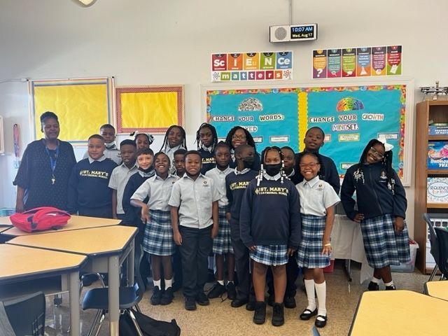 A group of children are posing for a picture in a classroom.