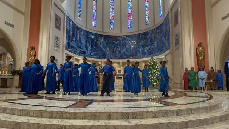 A group of people in blue dresses are dancing in a church.