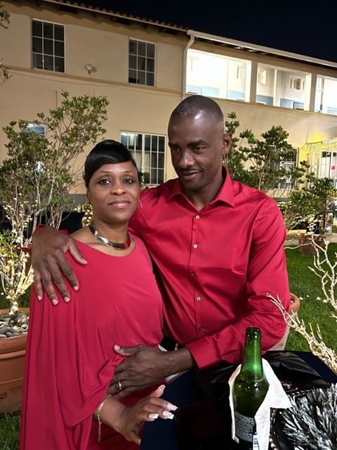 A man in a red shirt is hugging a woman in a red dress.