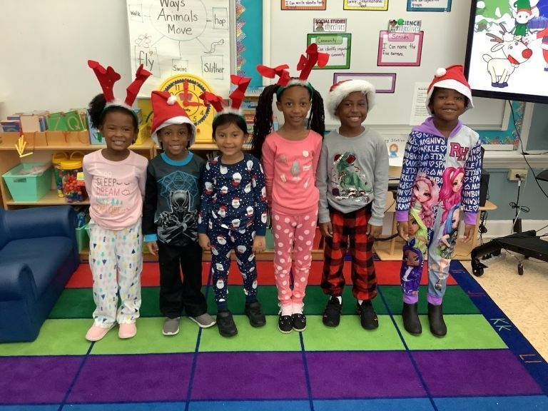 A group of children wearing pajamas and santa hats pose for a picture