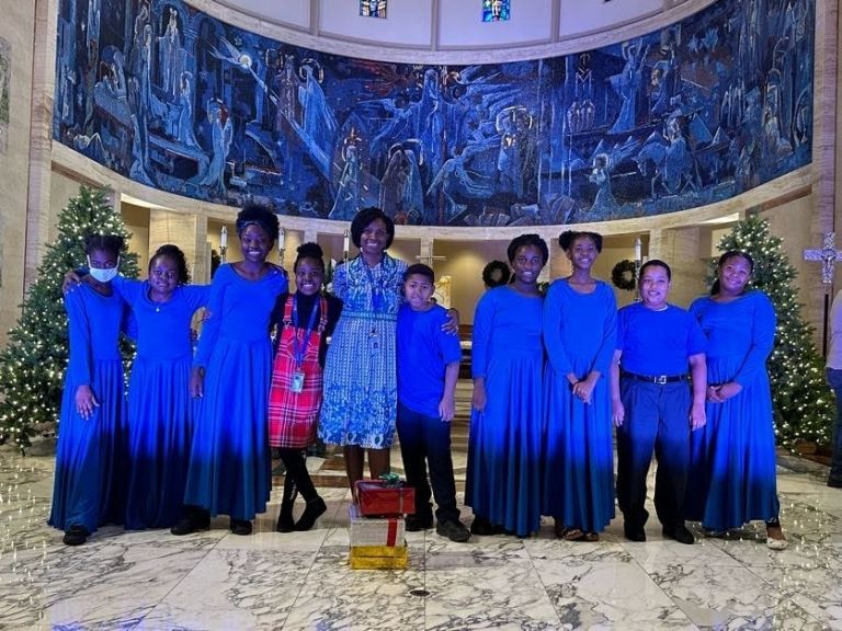 A group of people in blue dresses are posing for a picture.