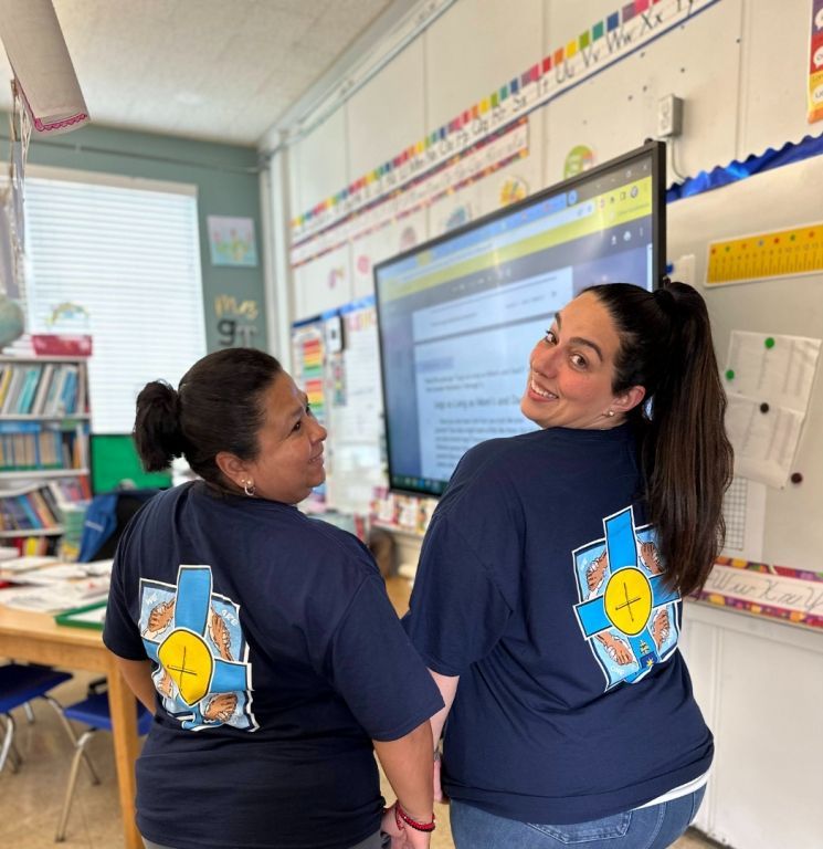 Two women standing next to each other in a classroom
