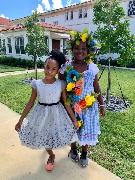 Two little girls standing next to each other in front of a building