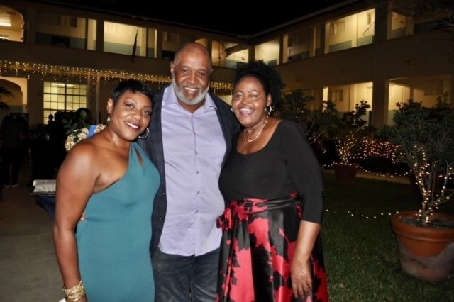 A man and two women pose for a picture in front of a building