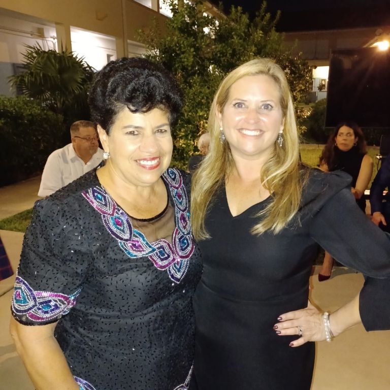 Two women are posing for a picture and one is wearing a black dress
