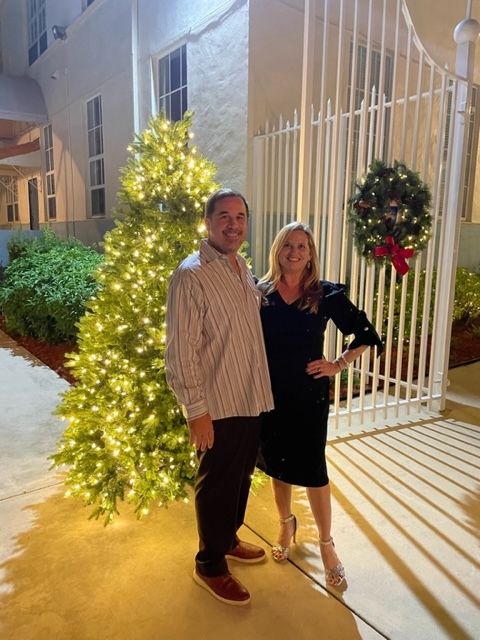 A man and a woman are standing in front of a christmas tree.