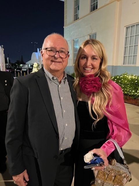 A man and a woman are posing for a picture in front of a building.