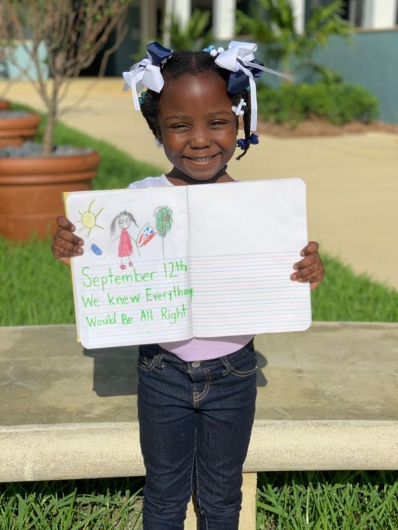 A little girl is holding a book with a drawing of a girl on it.