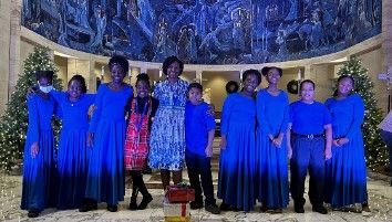 A group of people in blue dresses are posing for a picture.