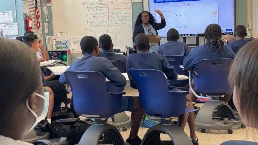 A teacher is giving a presentation to a group of students in a classroom.