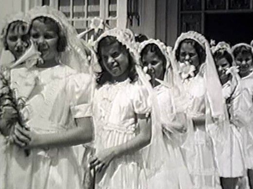 A group of girls in white dresses are standing in a line.