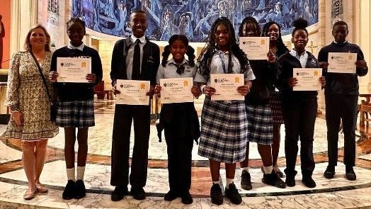 A group of people in school uniforms are standing next to each other holding certificates.