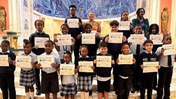 A group of children are standing in a church holding certificates.