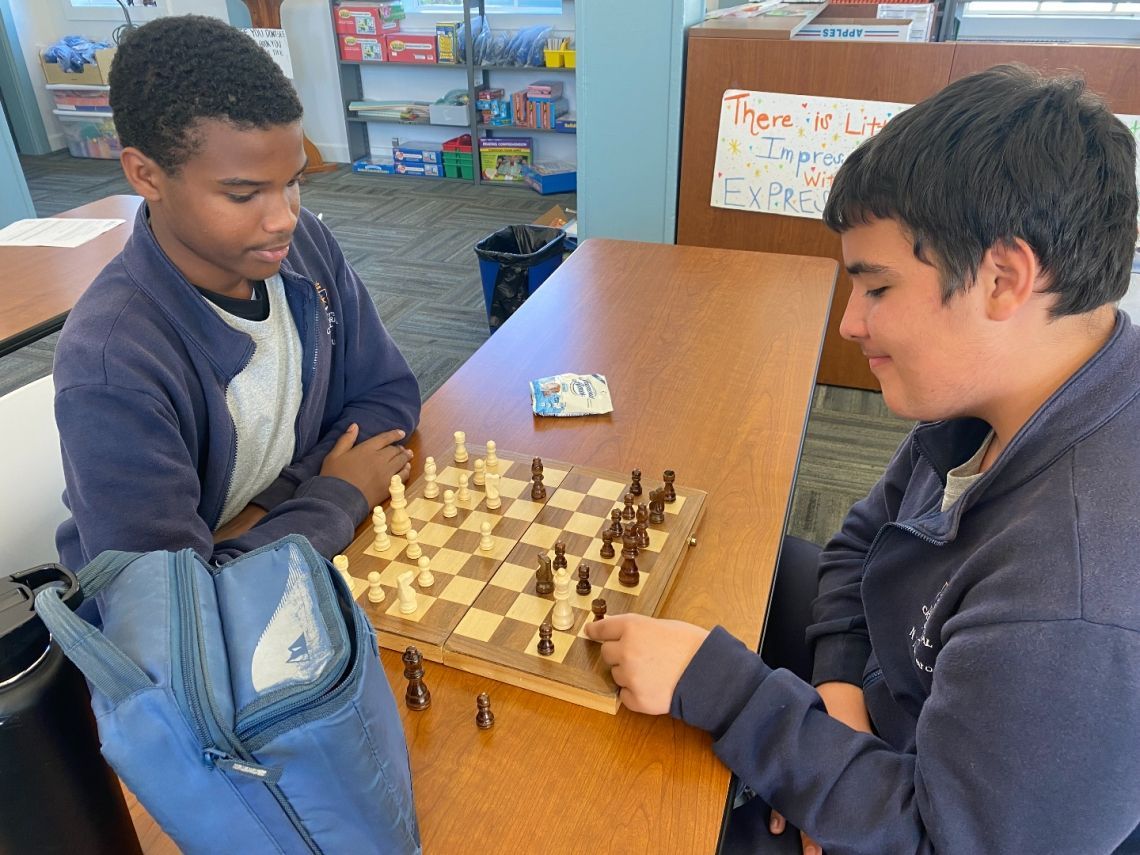 Two boys are playing a game of chess at a table