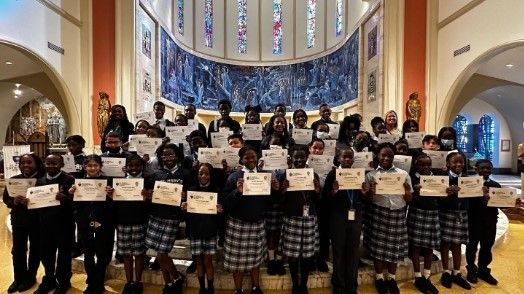 A group of children are standing in a church holding certificates.