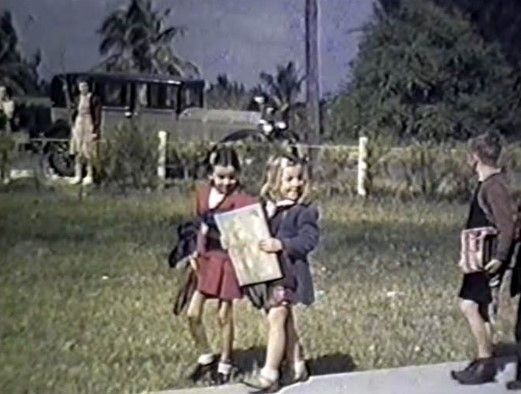 A group of children are standing on a sidewalk in front of a school bus.